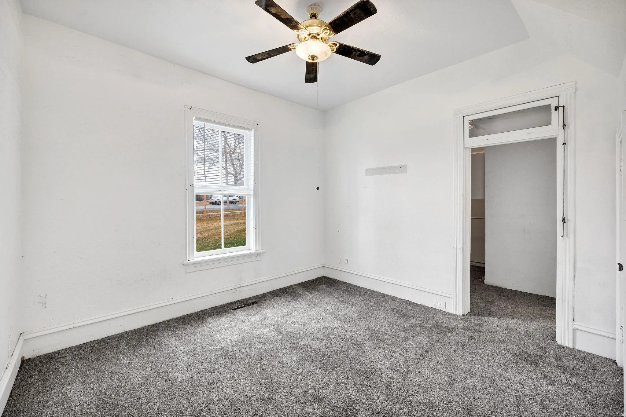 Carpeted spare room with a ceiling fan and baseboards