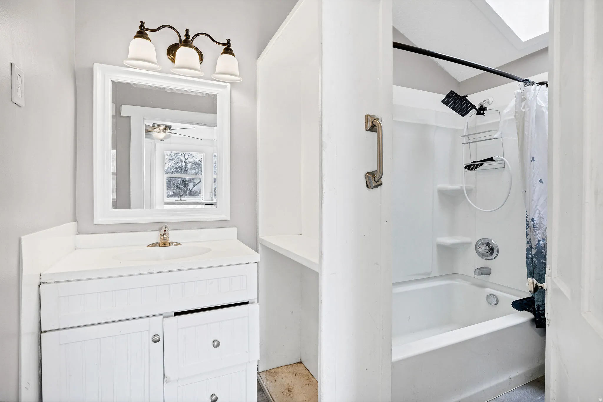 Full bath featuring vanity, shower / bath combo with shower curtain, and a skylight