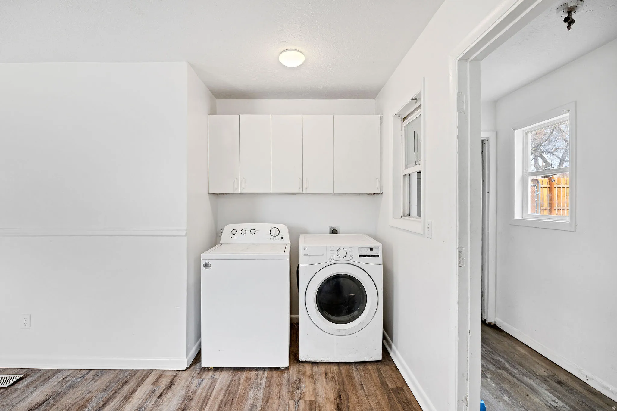 Laundry room with wood finished floors, cabinet space, and washing machine and dryer