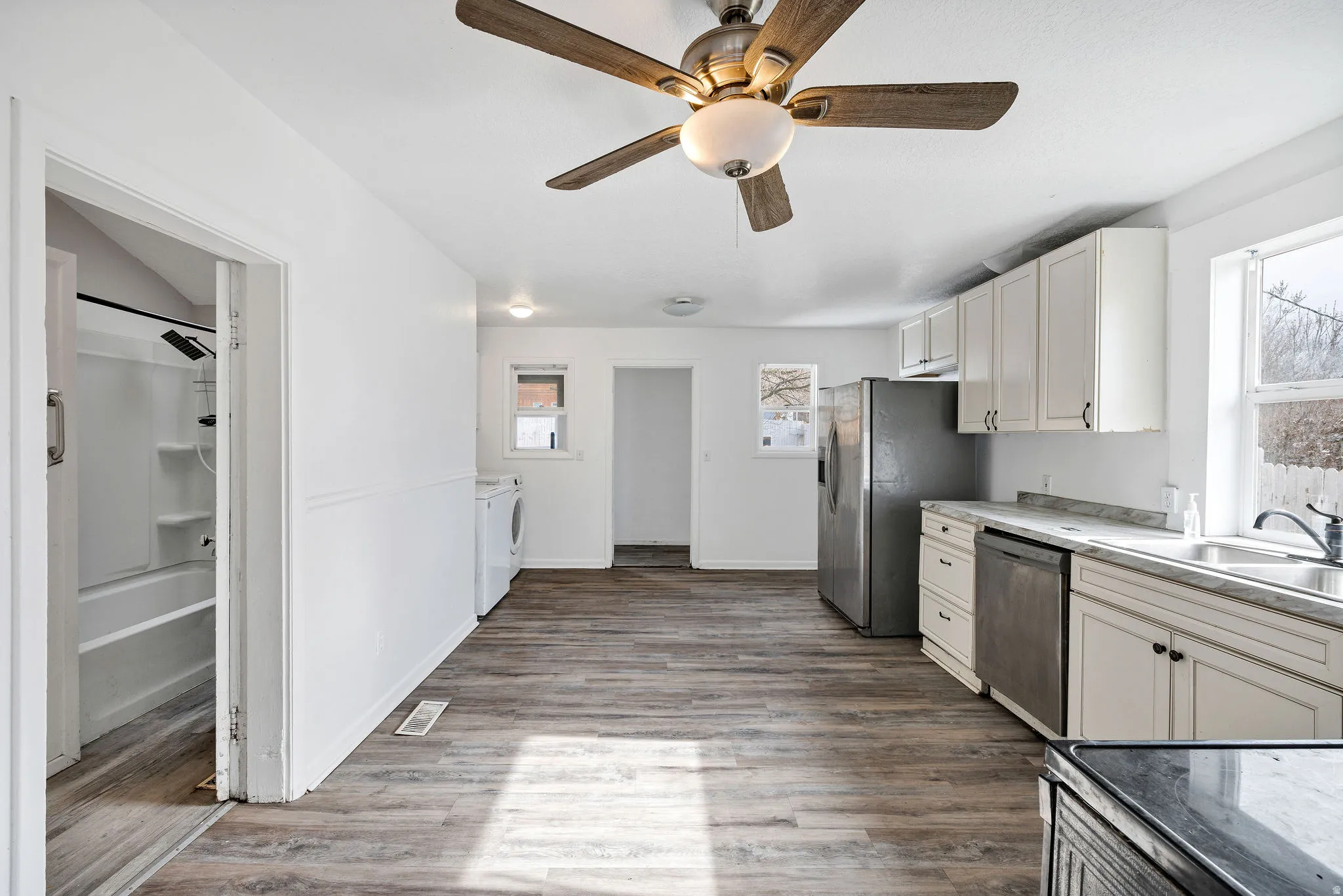 Kitchen featuring white cabinets, stainless steel appliances, light wood finished floors, and a ceiling fan