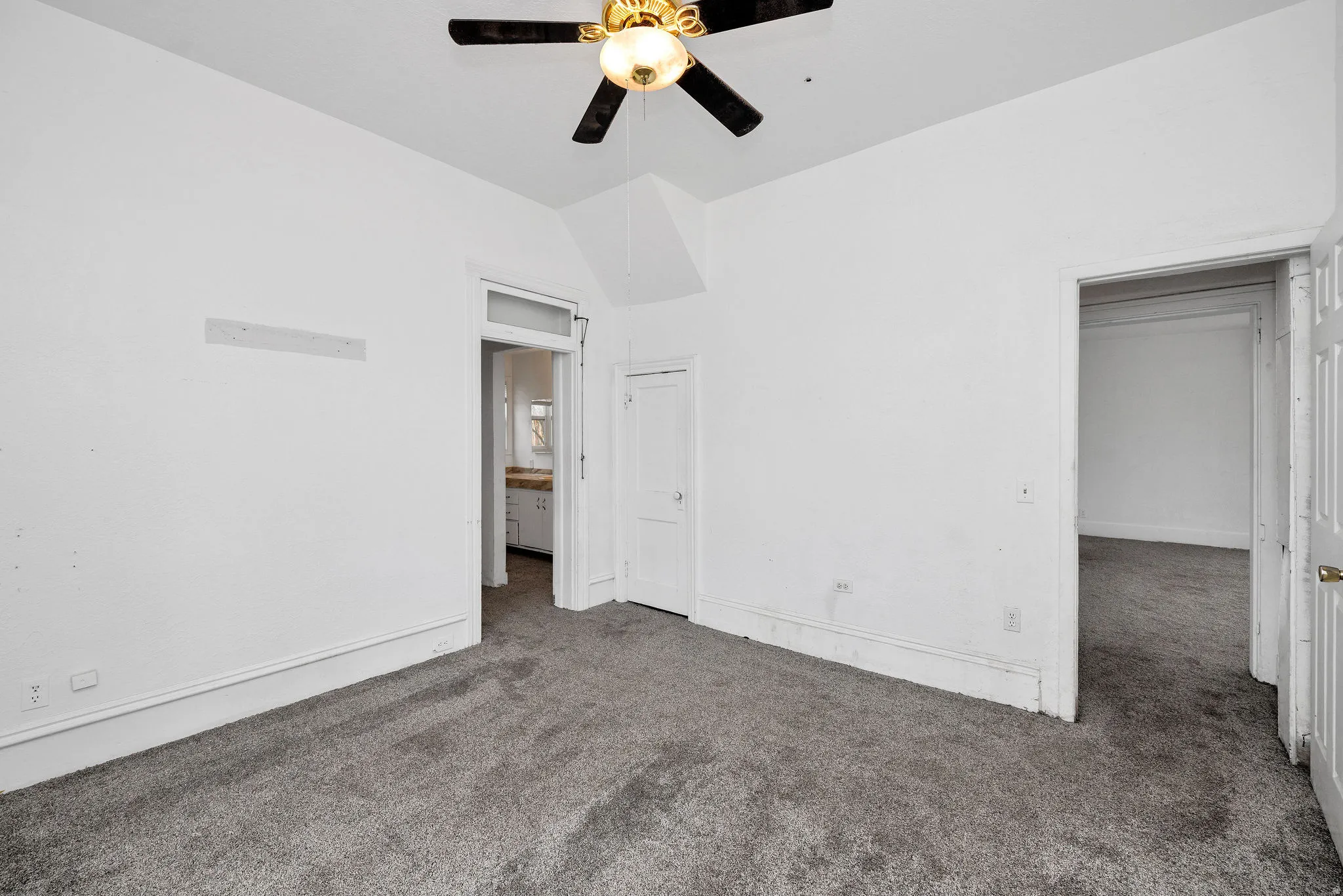 Unfurnished bedroom featuring carpet, vaulted ceiling, and ceiling fan