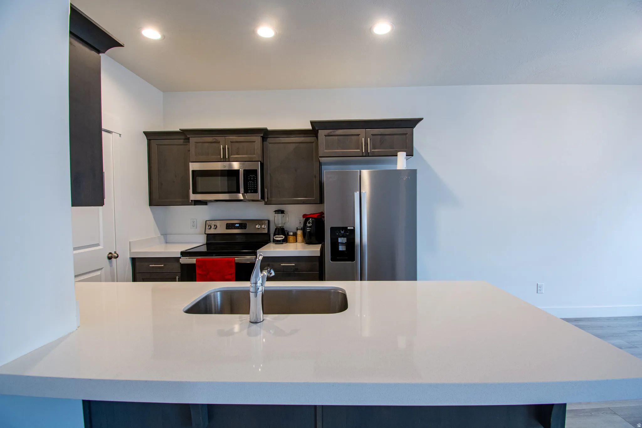 Kitchen with stainless steel appliances, dark brown cabinets, recessed lighting, a breakfast bar, and a peninsula