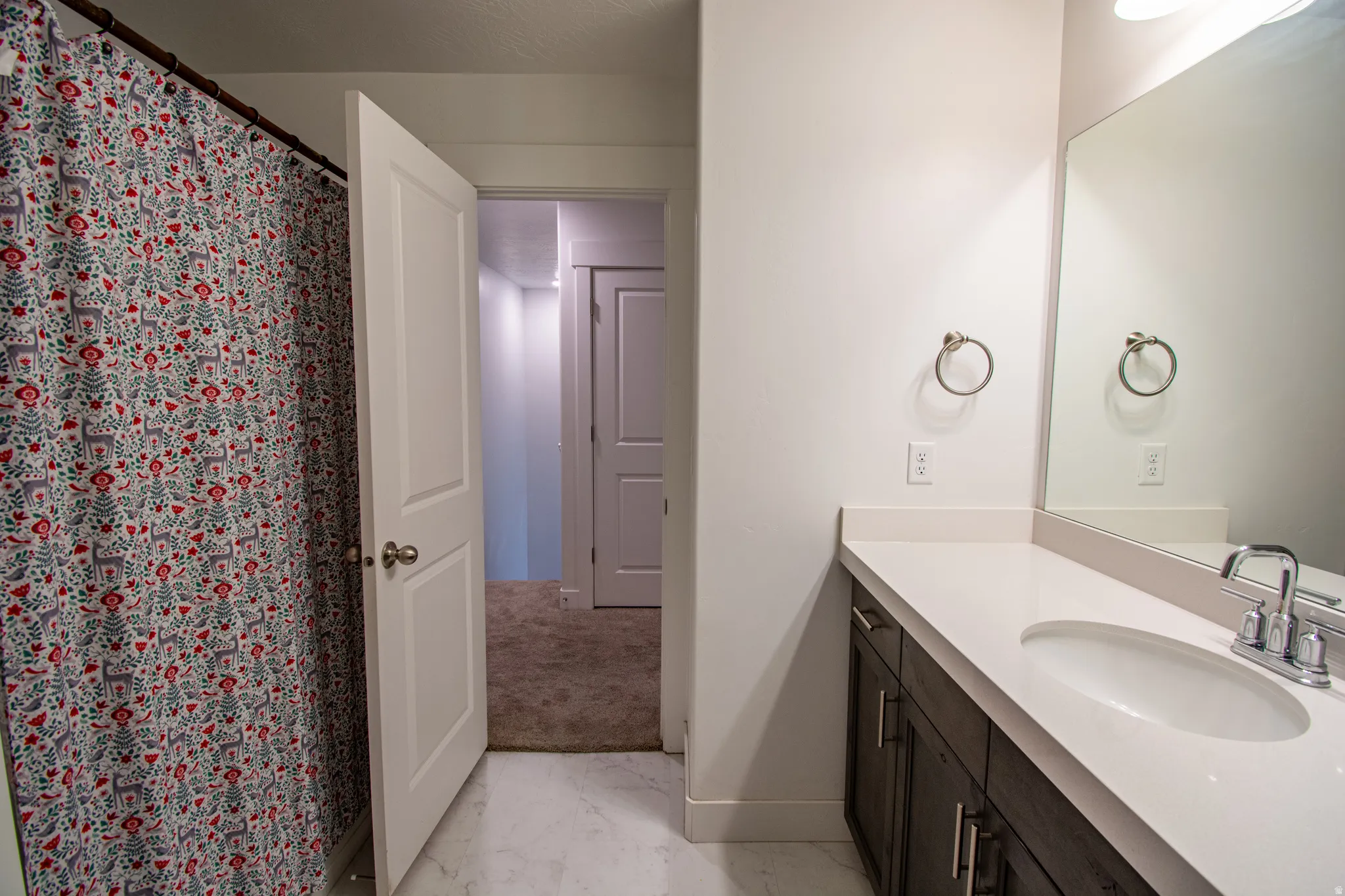 Bathroom with vanity, a shower with curtain, and light marble finish flooring