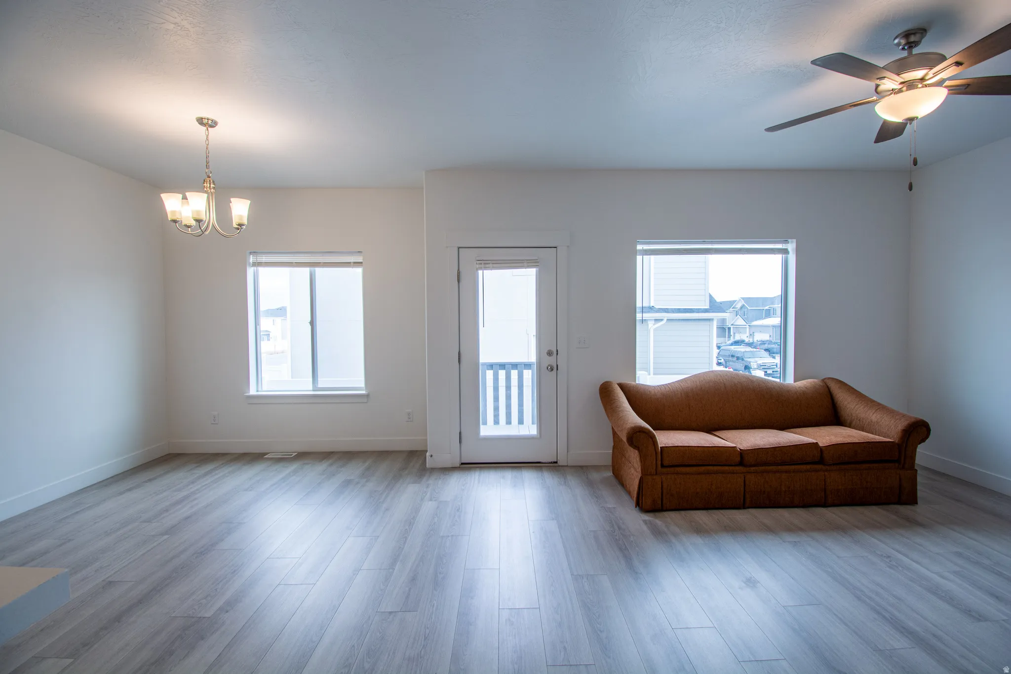 Living area with a chandelier, a ceiling fan, wood finished floors, and plenty of natural light