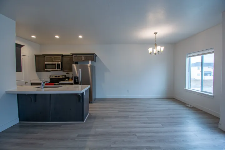 Kitchen with a breakfast bar area, appliances with stainless steel finishes, dark brown cabinets, a chandelier, and light wood-style floors