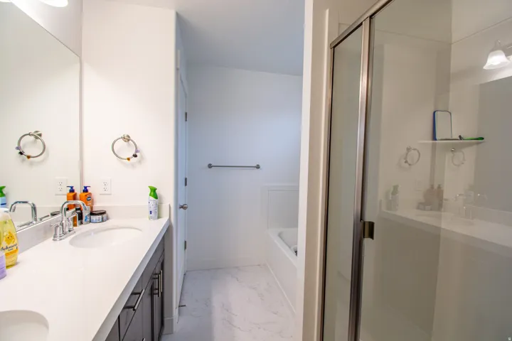 Bathroom featuring double vanity, a shower stall, light marble finish flooring, and a bath