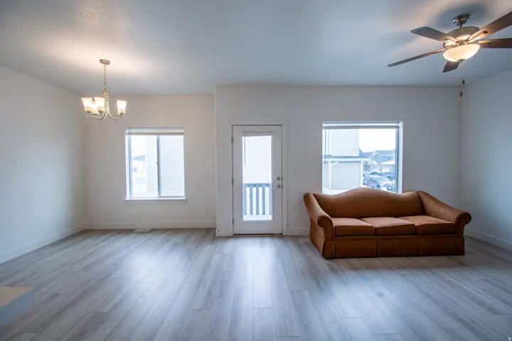 Living area with a chandelier, a ceiling fan, wood finished floors, and plenty of natural light