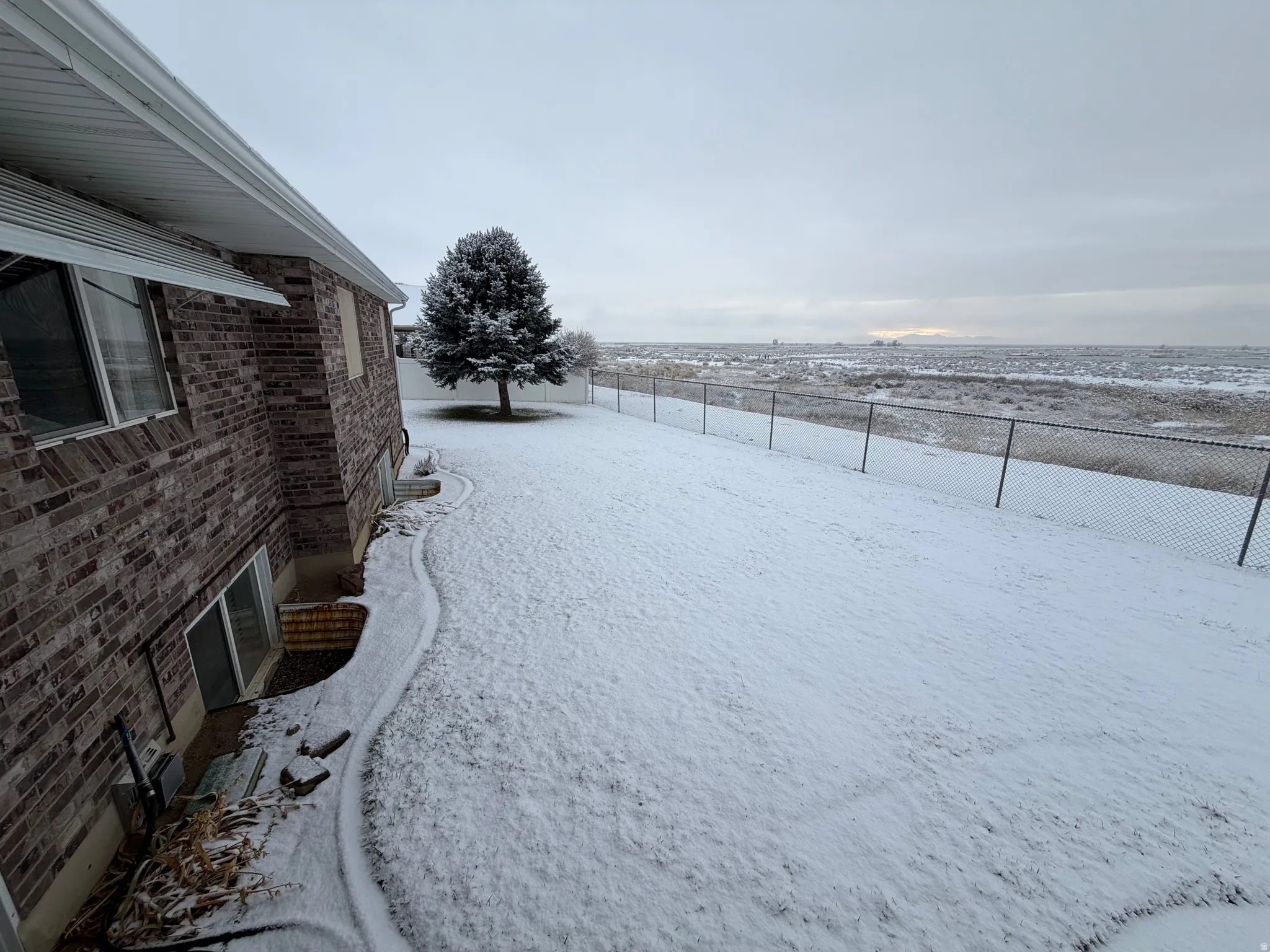 Yard covered in snow with a fenced backyard