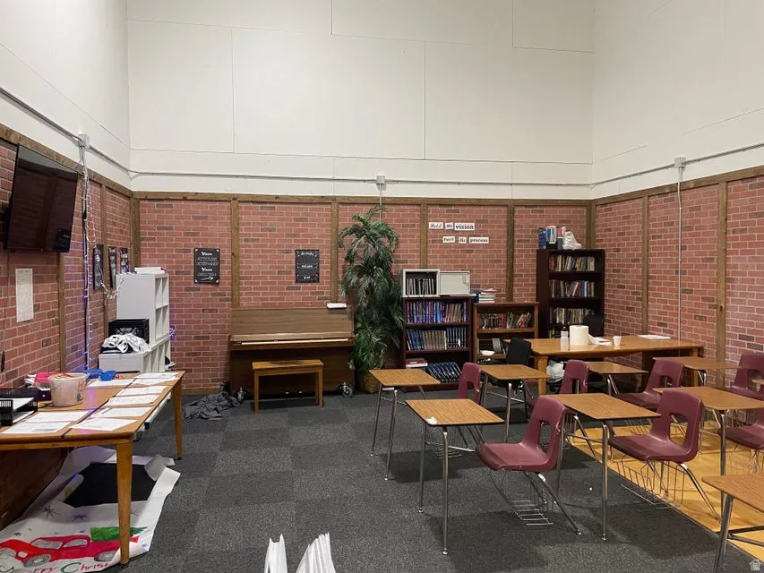 Misc room featuring a towering ceiling and brick wall