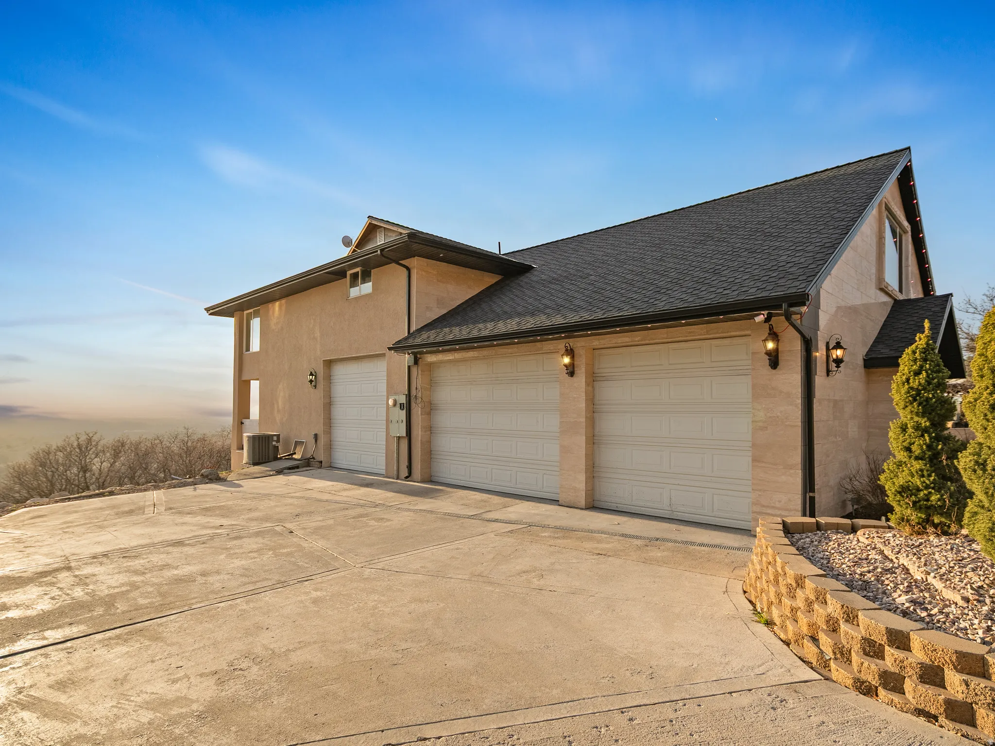View of side of property with roof with shingles, concrete driveway, and a garage