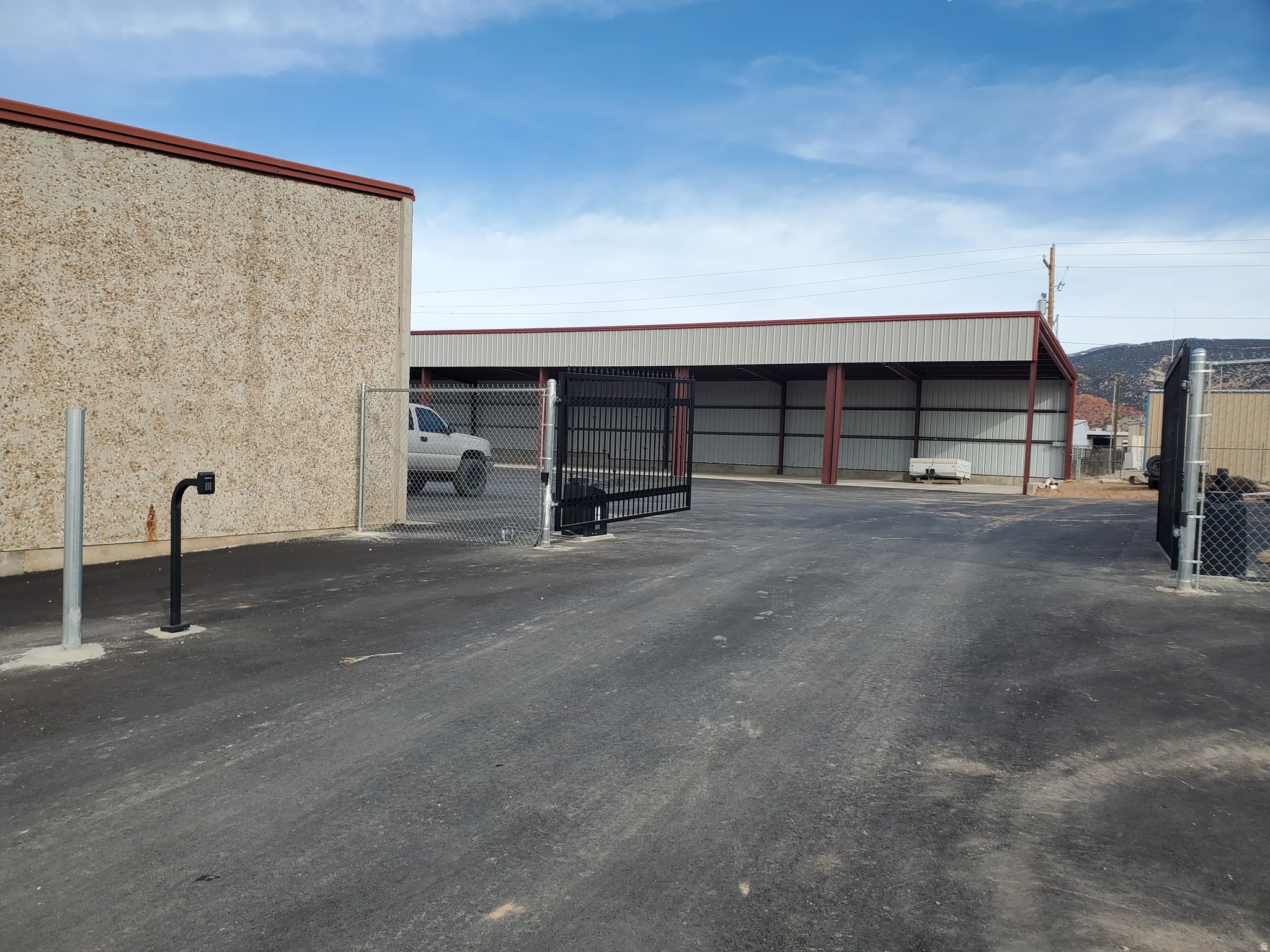 View of vehicle parking with a gate and an outbuilding