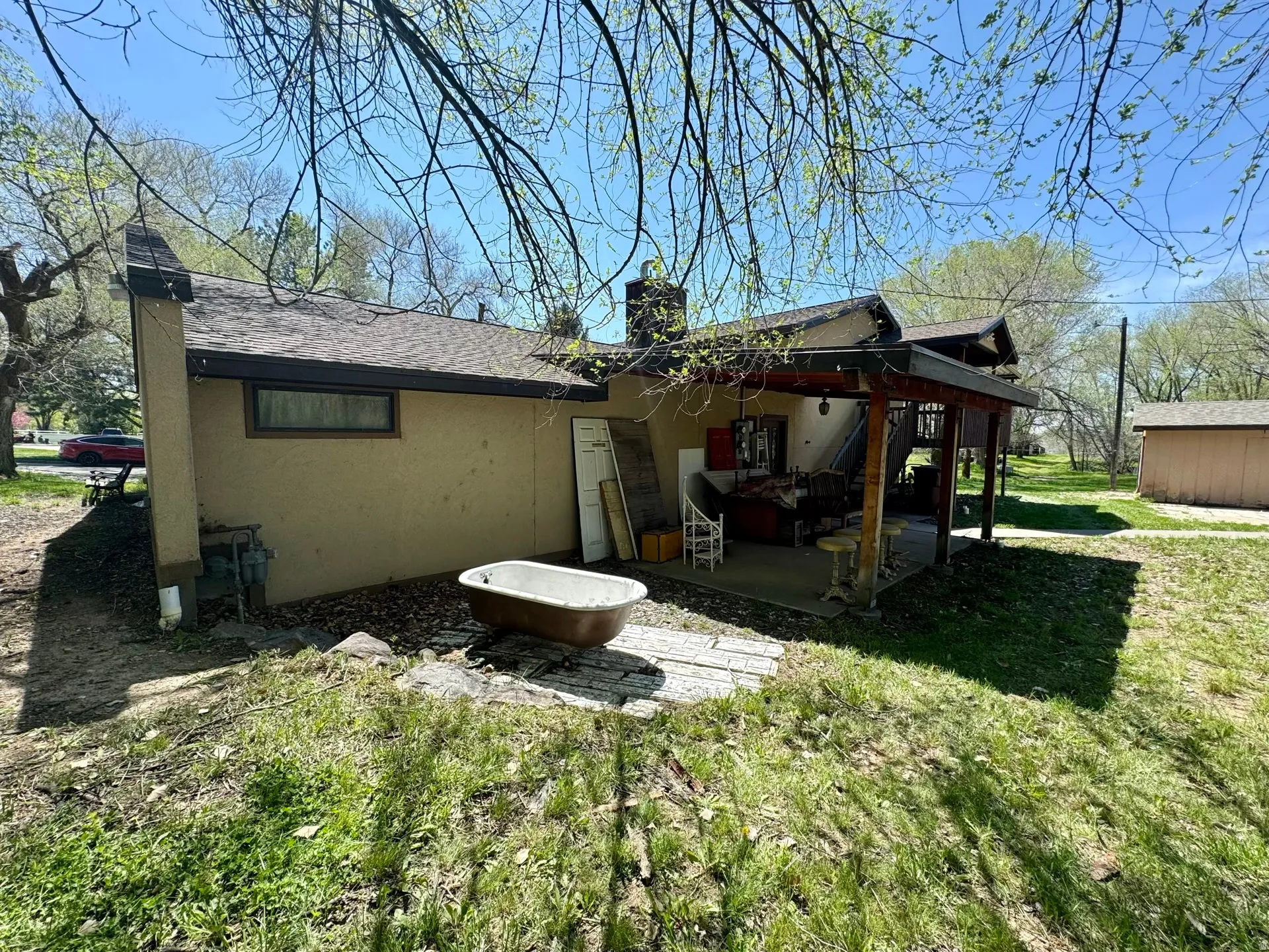 Back of property featuring a chimney, stucco siding, a patio area, a shingled roof, and a lawn