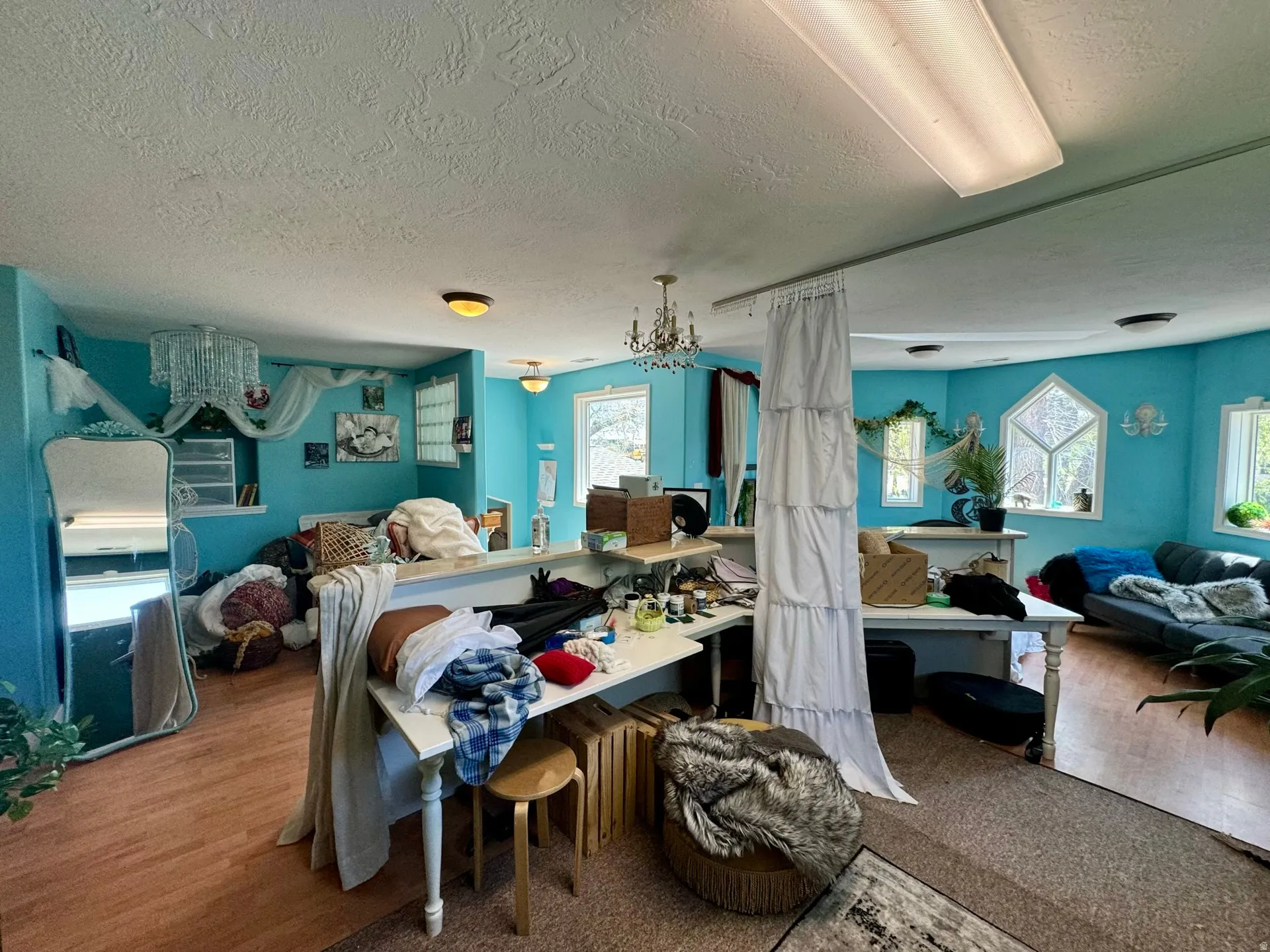 Bedroom with a textured ceiling, multiple windows, a chandelier, and wood finished floors