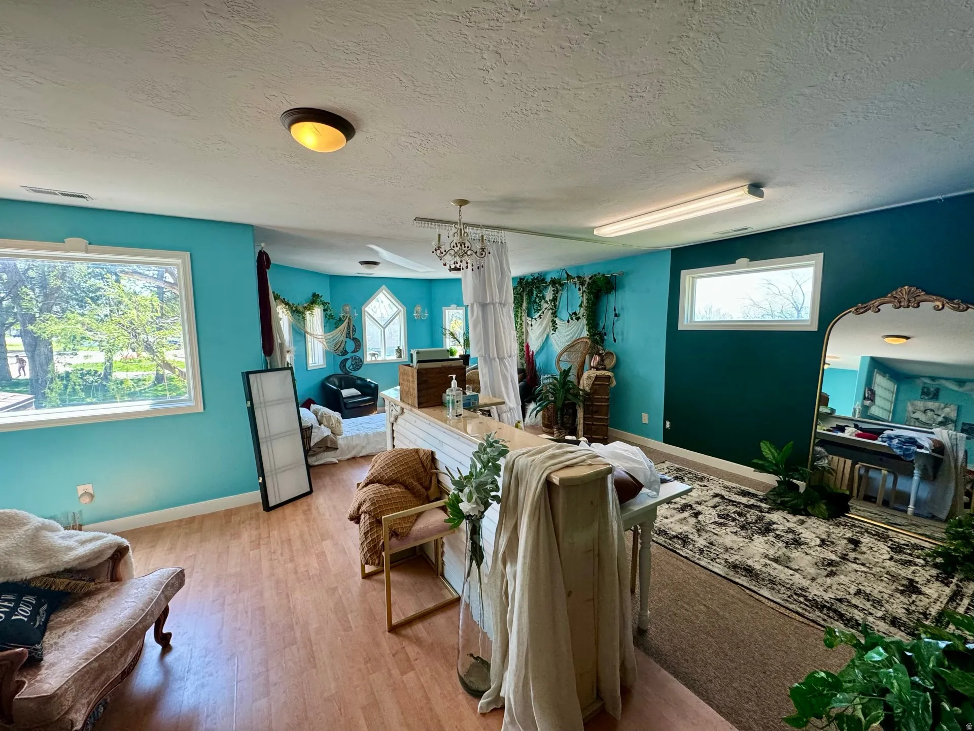 Living area with light wood finished floors, a textured ceiling, and a chandelier