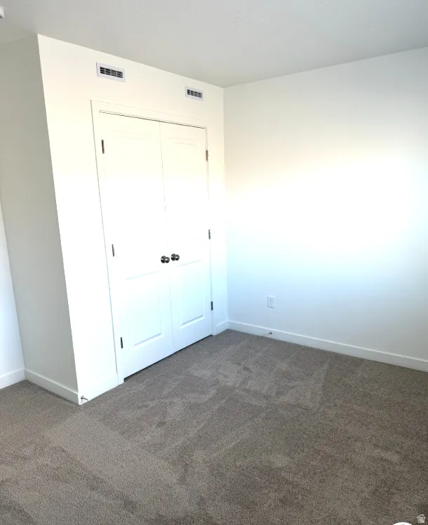 Unfurnished bedroom featuring dark carpet and a closet