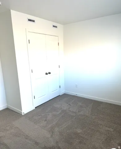 Unfurnished bedroom featuring dark carpet and a closet