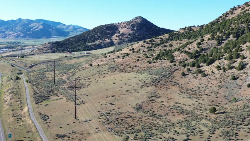 Expansive mountain landscape with diverse terrain, featuring scattered evergreen trees and natural vegetation