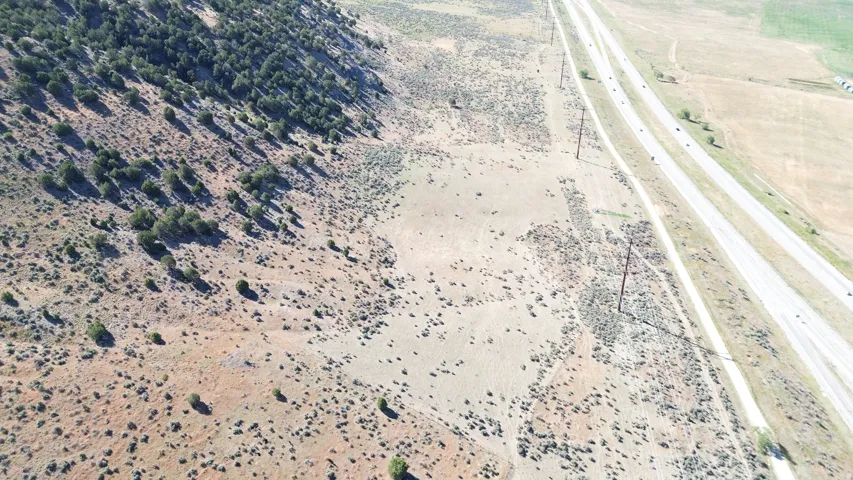 Expansive undeveloped land featuring natural desert vegetation, varied terrain, and a highway frontage