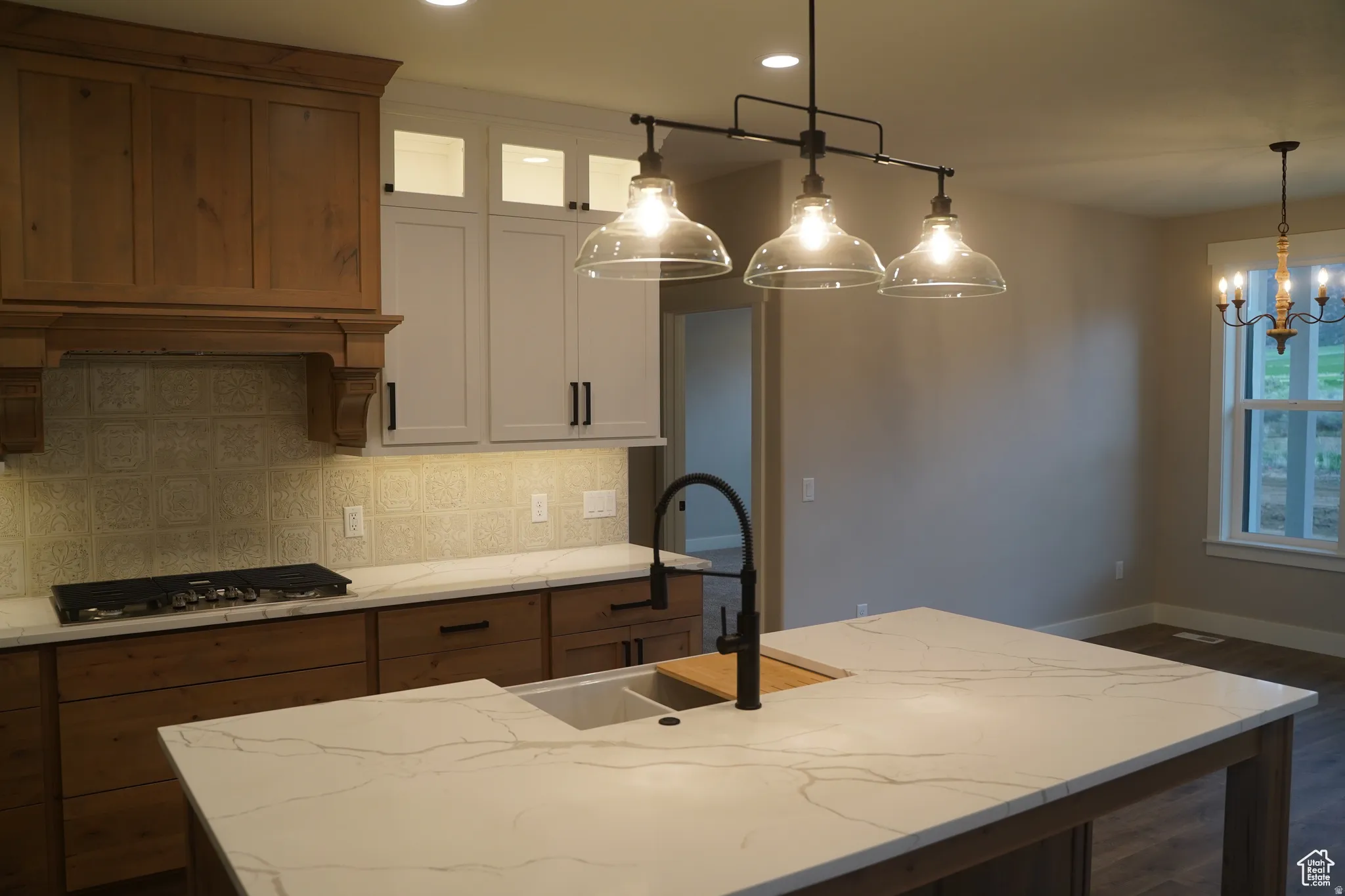 Kitchen featuring white cabinets, light stone countertops, tasteful backsplash, decorative light fixtures, and recessed lighting