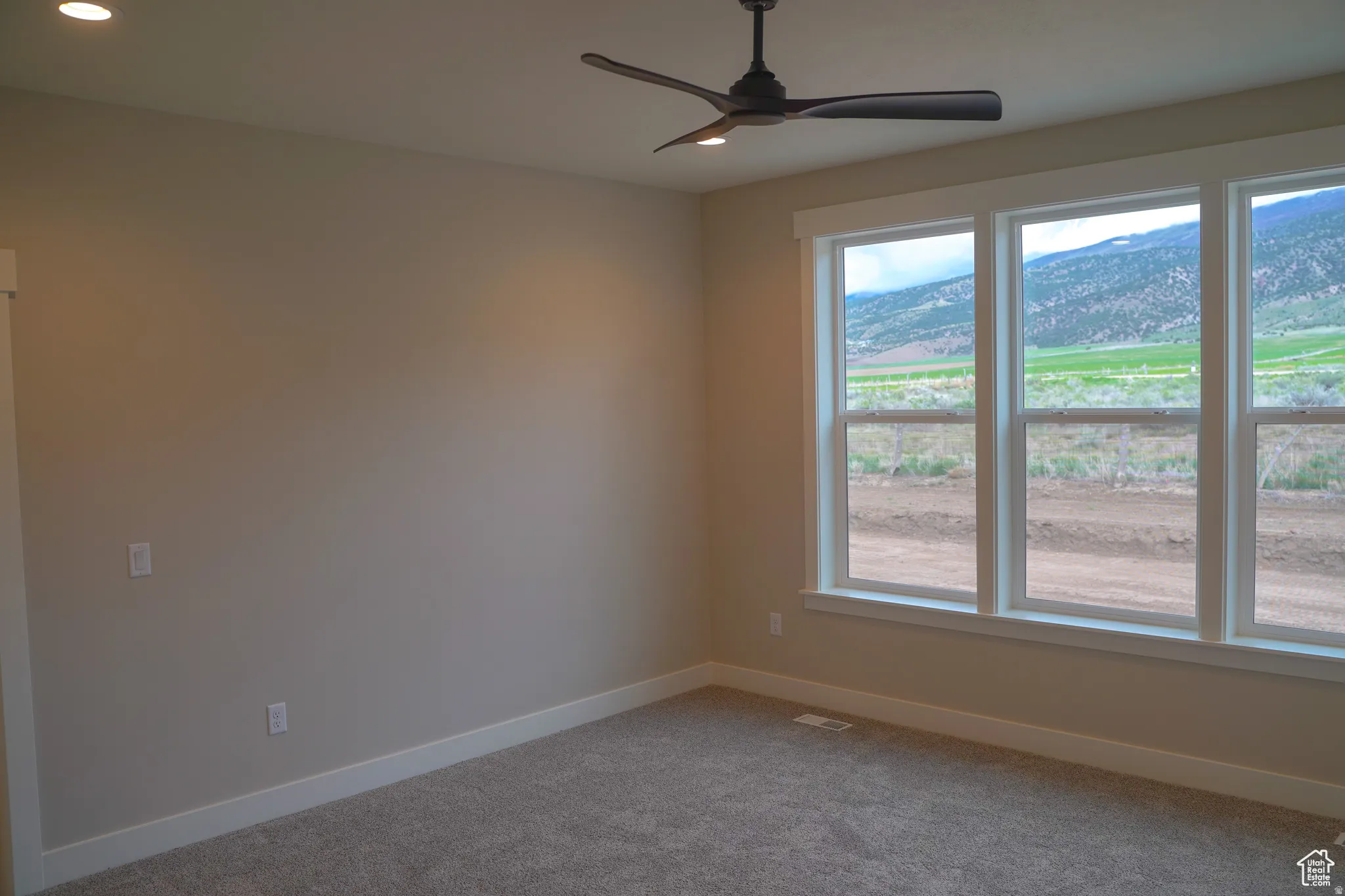 Empty room with a ceiling fan, carpet, a mountain view, and recessed lighting
