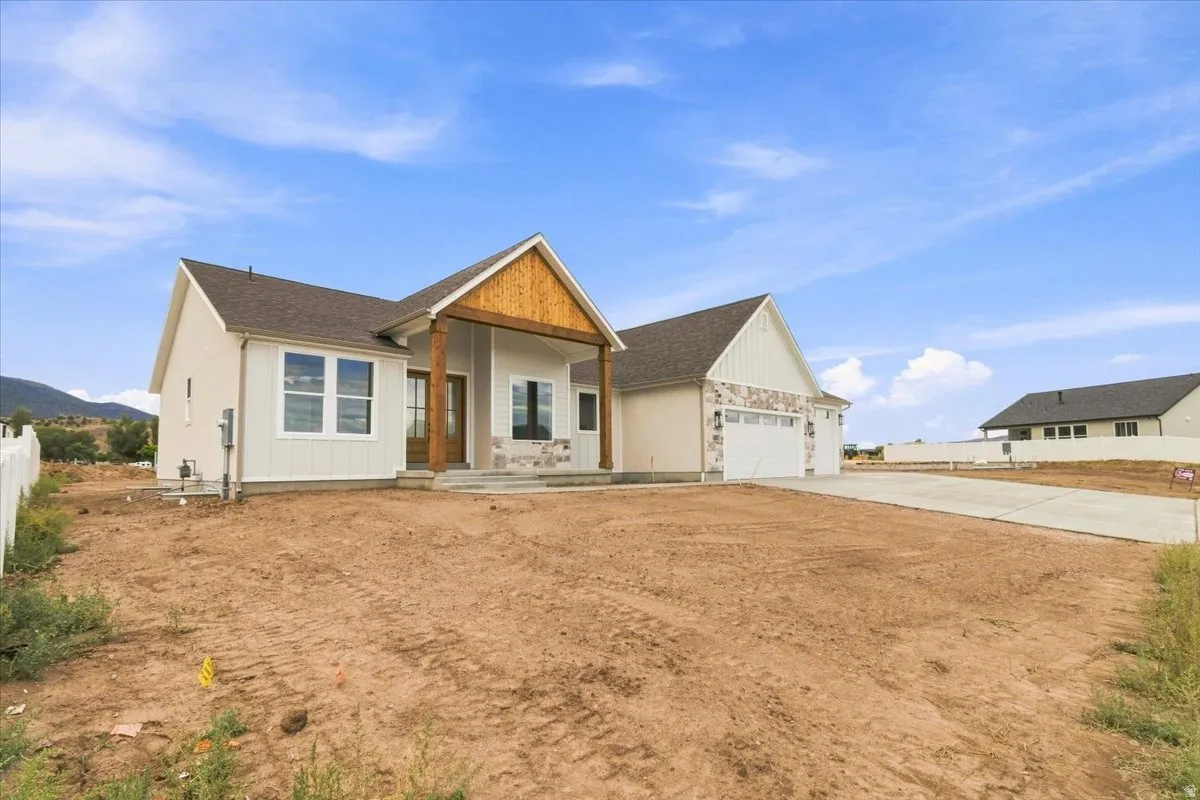 Modern farmhouse architecture with a covered entry, wood-finish columns, stone accents, and a two-car garage