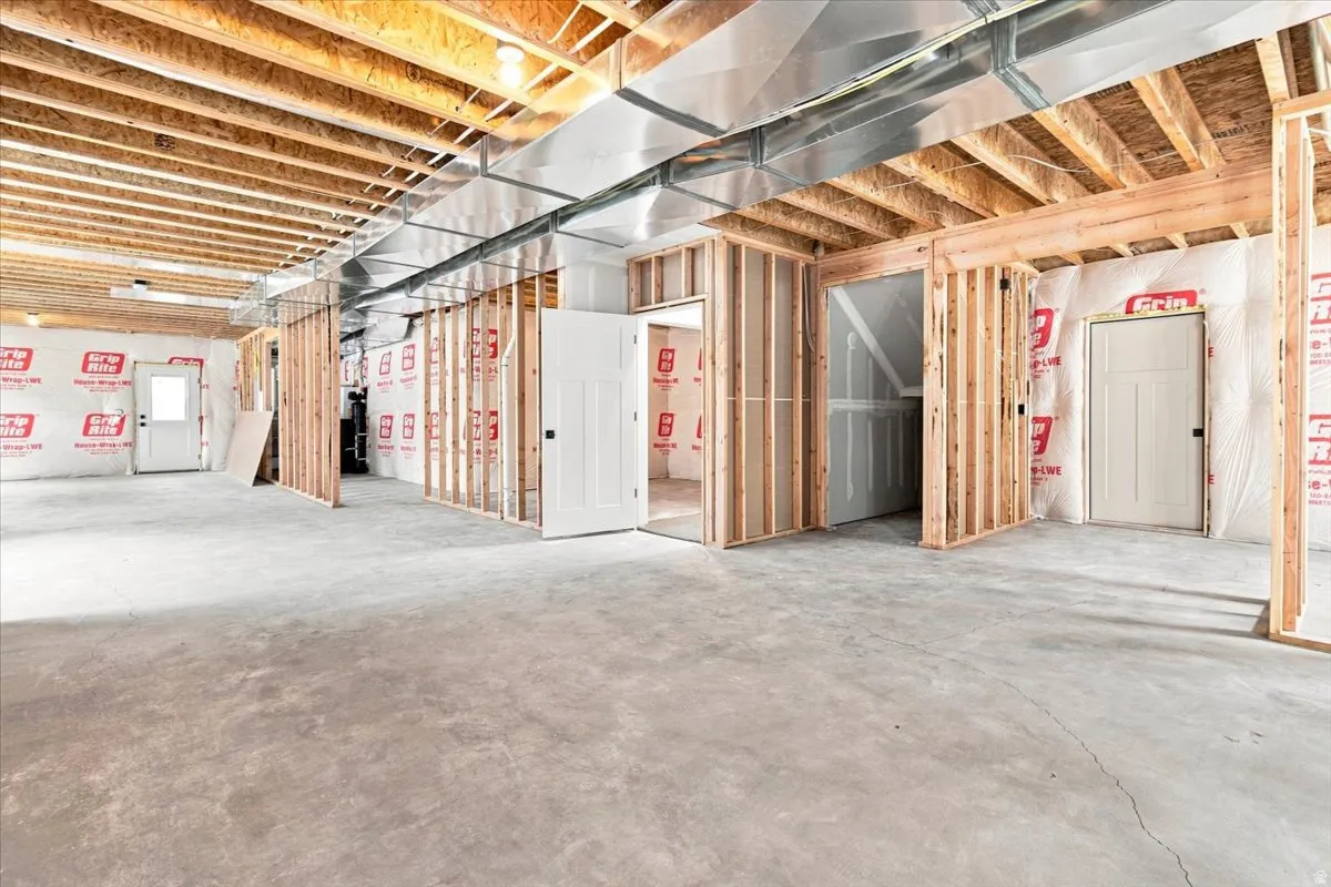 Unfinished basement with exposed wood joists, concrete flooring, framed interior walls, white panel doors, and visible ductwork