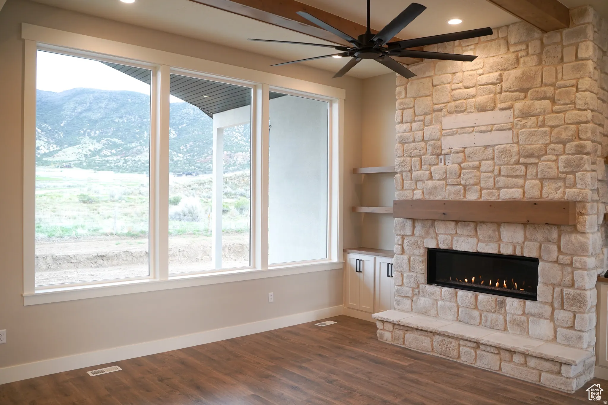 Unfurnished living room featuring a mountain view, dark wood-style flooring, beamed ceiling, a fireplace, and recessed lighting