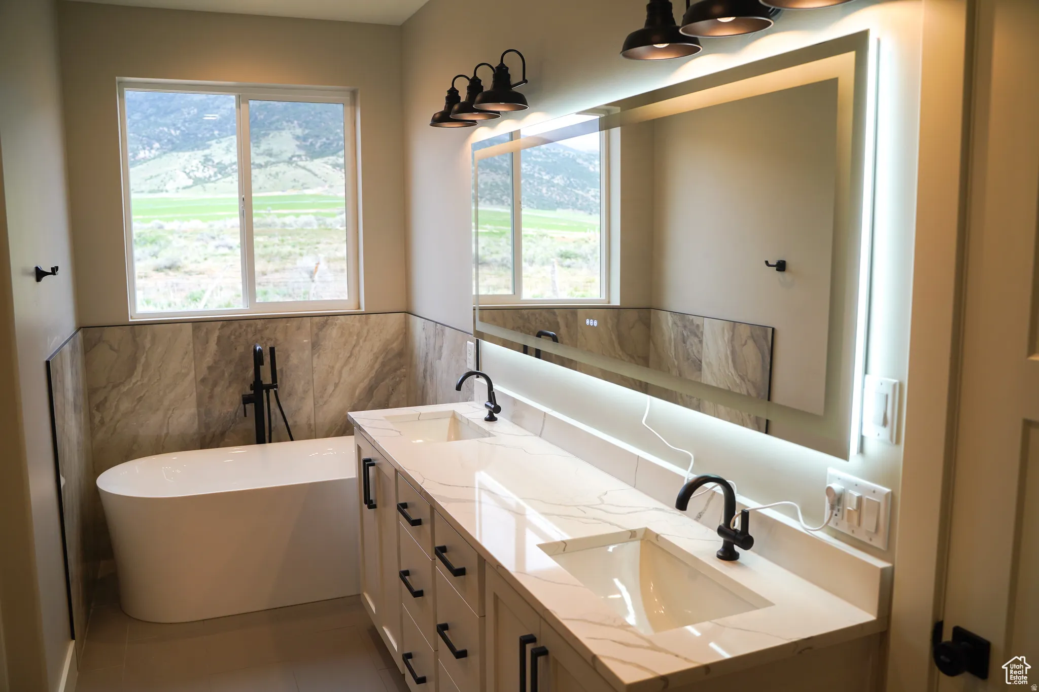 Bathroom with a soaking tub, double vanity, plenty of natural light, and tile walls