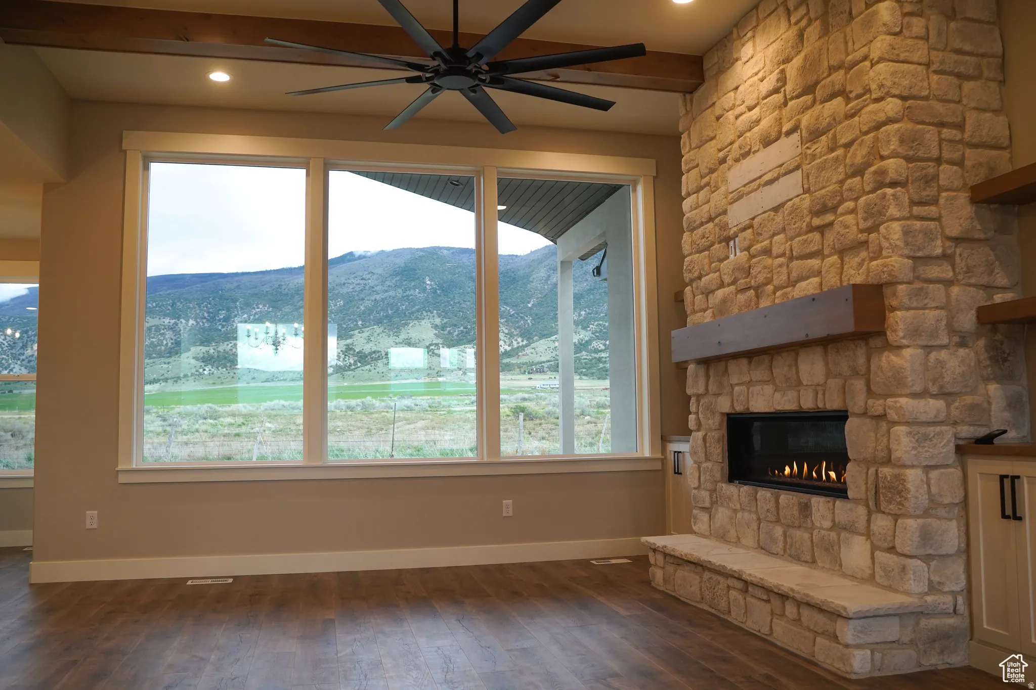 Unfurnished living room with a mountain view, dark wood-style flooring, a stone fireplace, ceiling fan, and recessed lighting