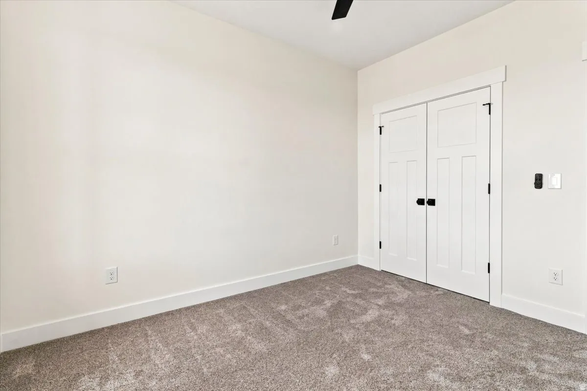 Neutral-toned walls, plush carpeting, white trim, and a ceiling fan