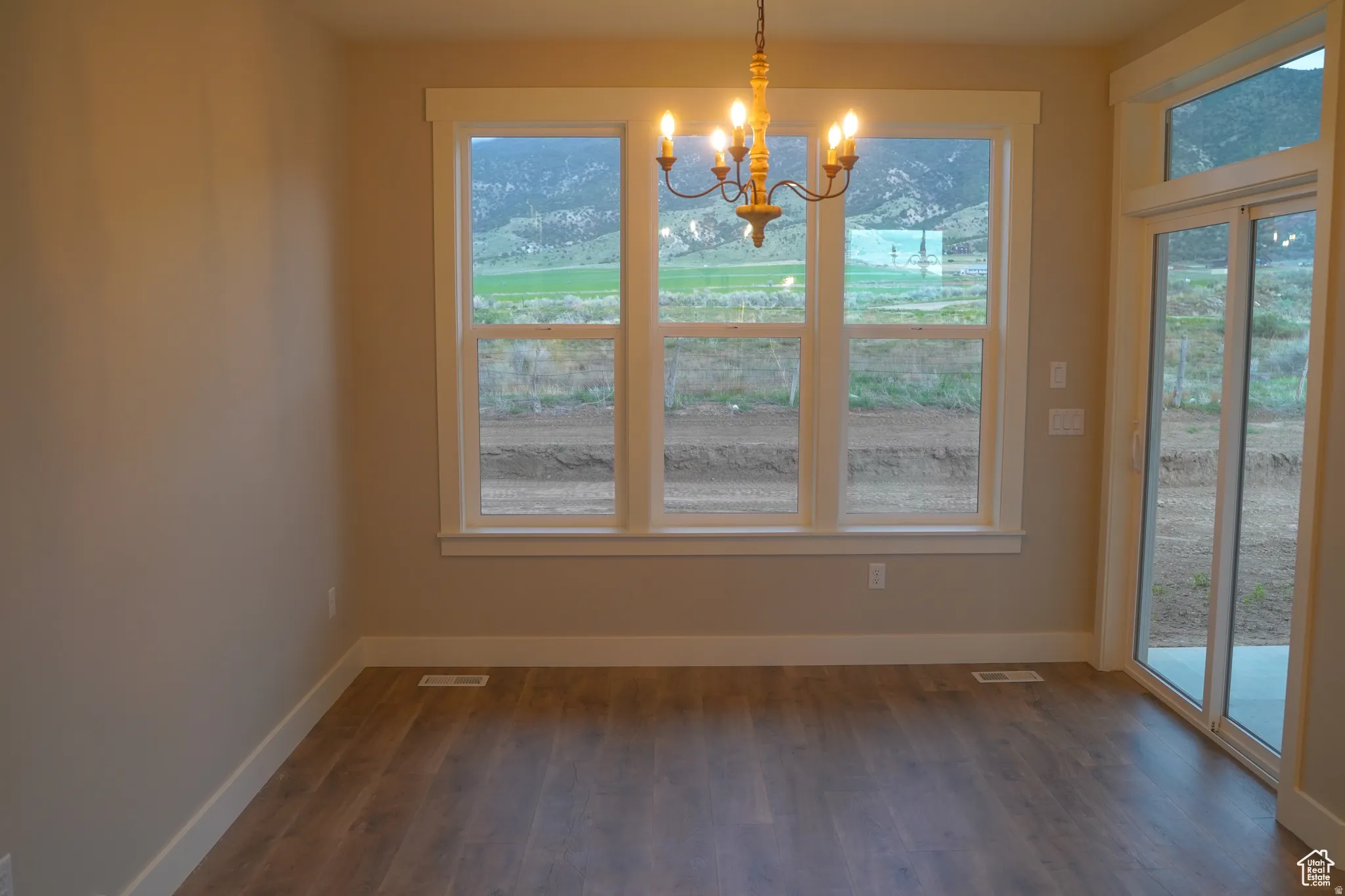 Unfurnished dining area featuring dark wood-type flooring and a chandelier