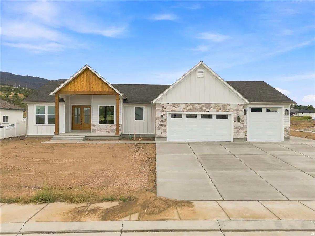 Contemporary exterior with stone accent siding, a covered entry, and a two-car garage