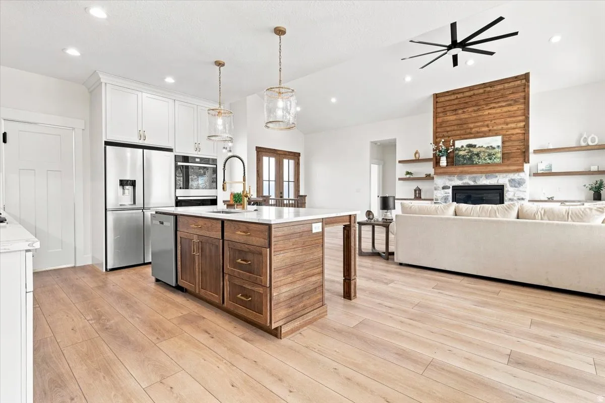 Light wood-finish flooring throughout, bright white walls, and a wood-paneled fireplace with a stone surround
