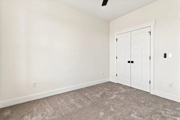 Neutral-toned walls, plush carpeting, white trim, and a ceiling fan