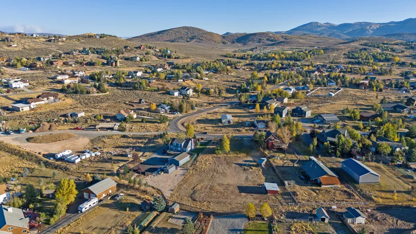 Aerial view of property and surrounding area featuring nearby suburban area and mountains
