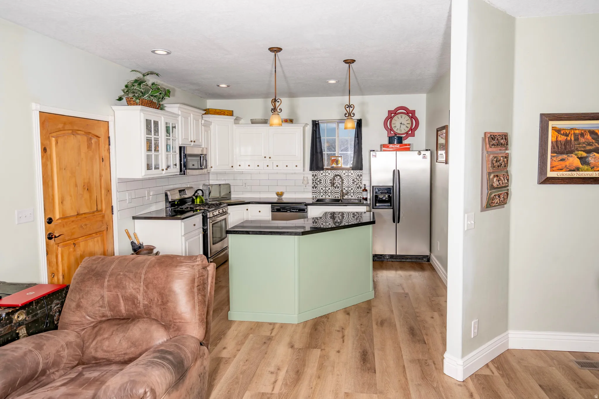 Kitchen with stainless steel appliances, glass insert cabinets, a center island, hanging light fixtures, and white cabinets