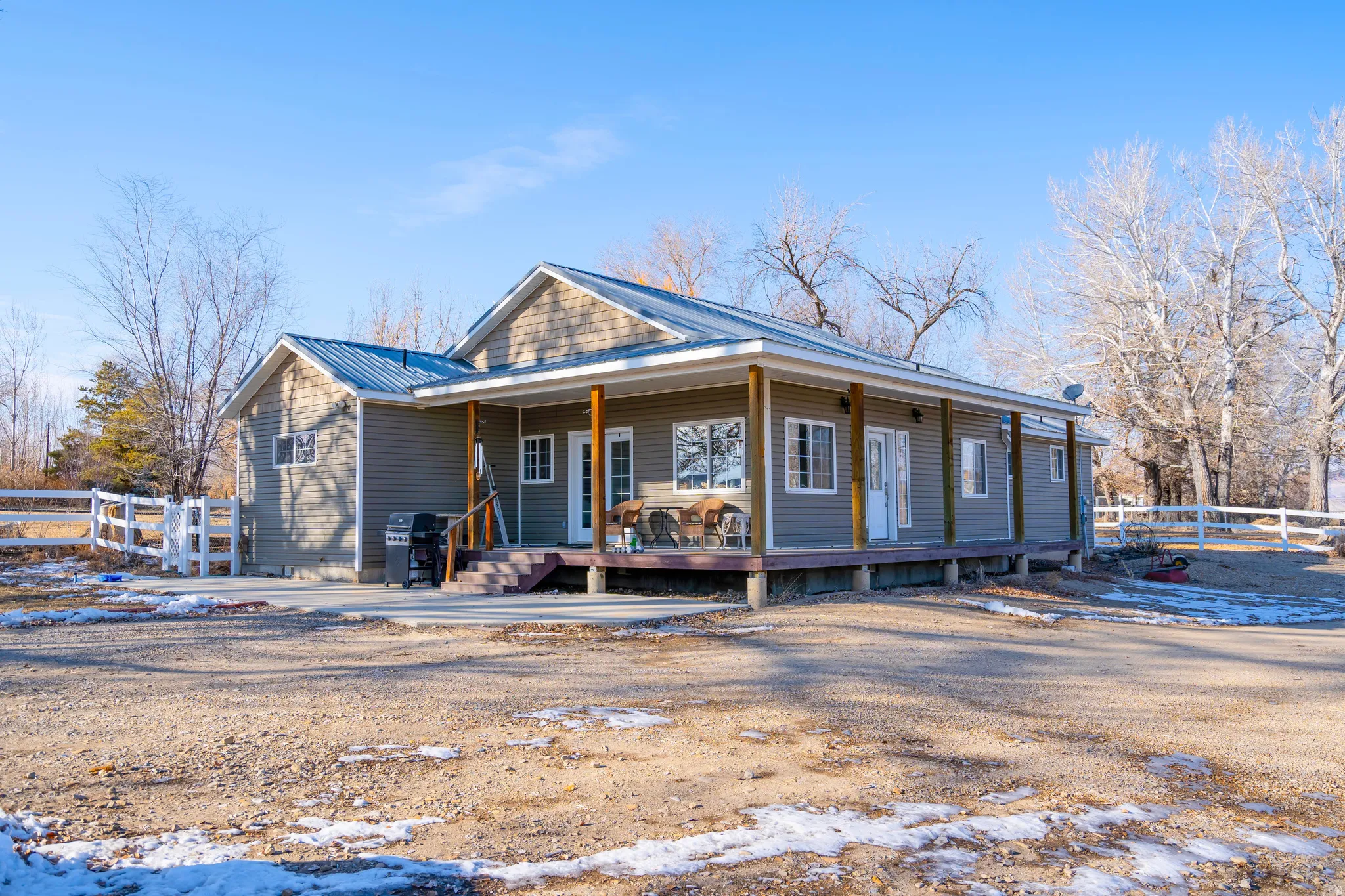 Snow covered back of property with covered porch and a metal roof