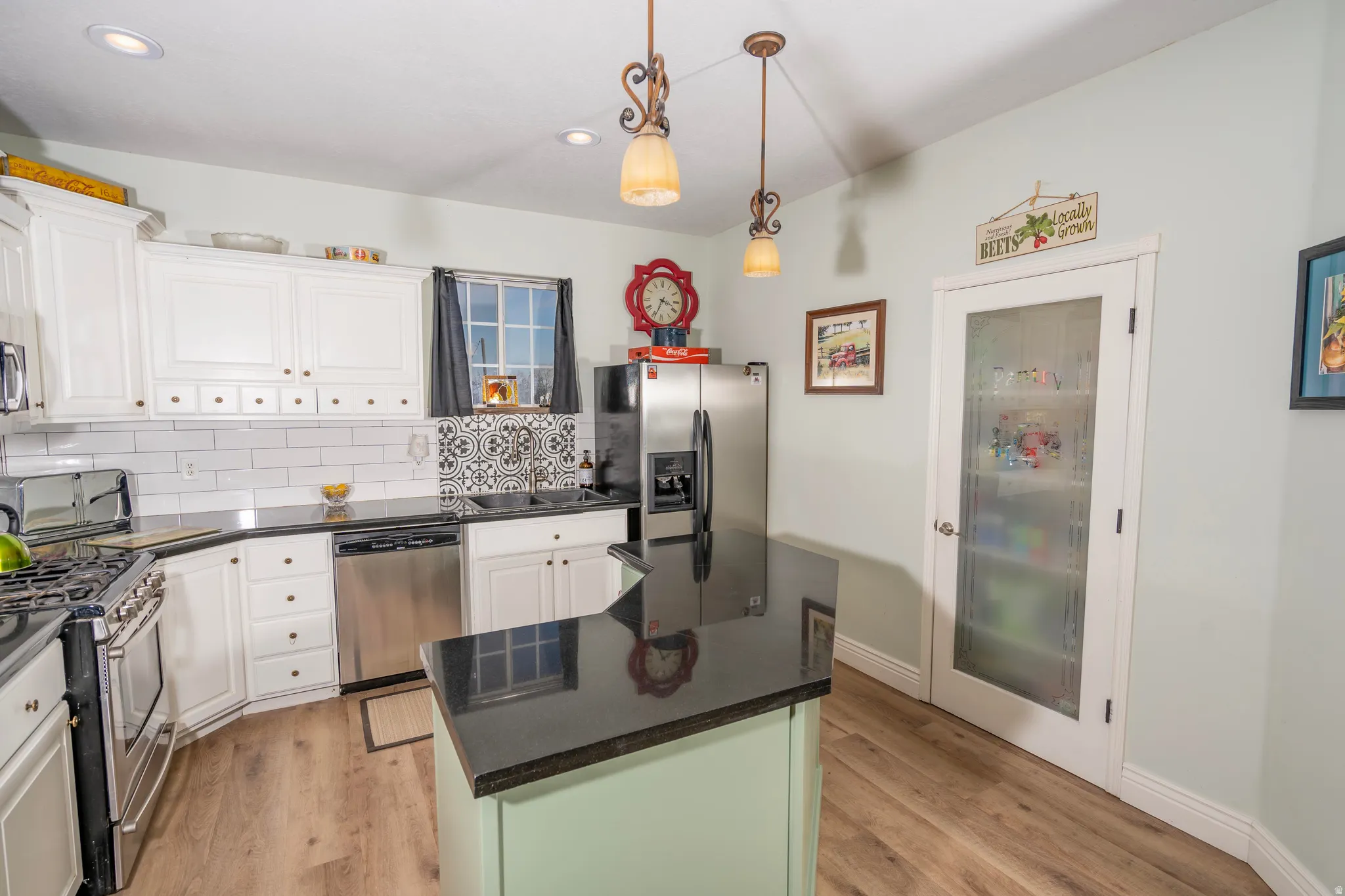 Kitchen with white cabinetry, hanging light fixtures, appliances with stainless steel finishes, light wood finished floors, and recessed lighting