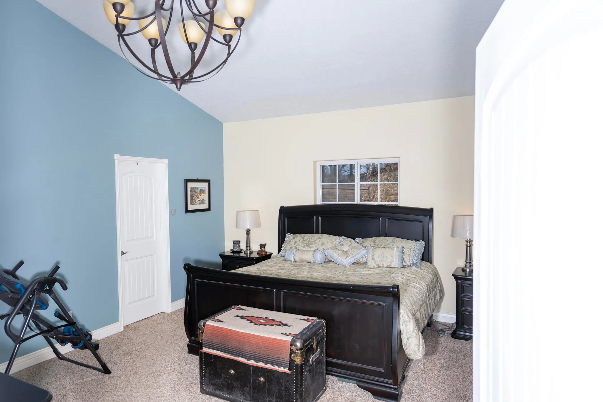 Bedroom with vaulted ceiling, carpet, and a chandelier