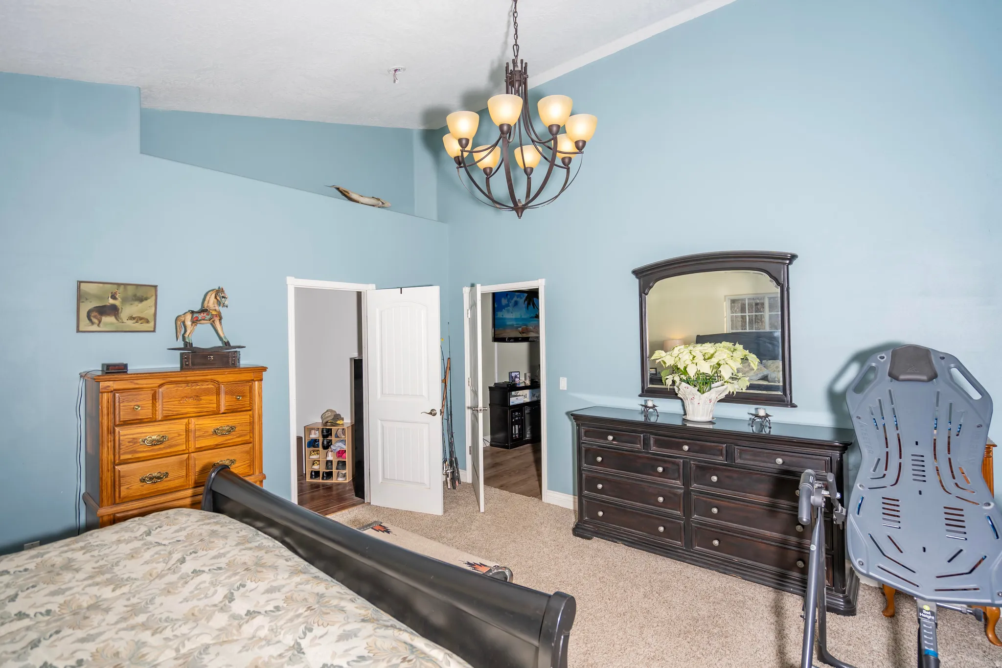 Carpeted bedroom with a chandelier and high vaulted ceiling