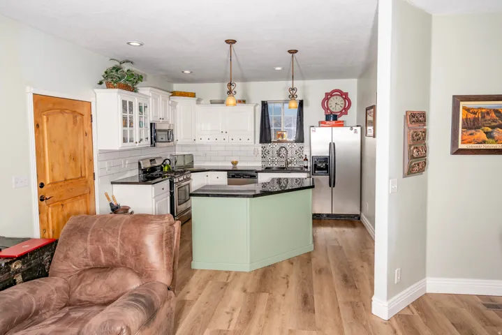 Kitchen with stainless steel appliances, glass insert cabinets, a center island, hanging light fixtures, and white cabinets