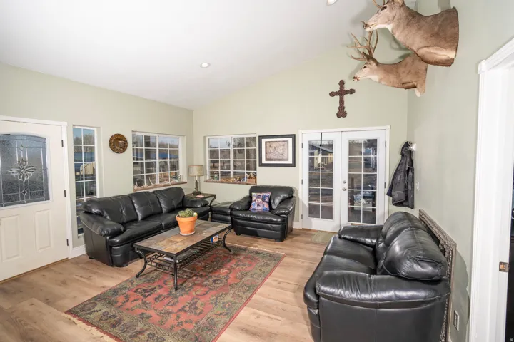 Living area with french doors, high vaulted ceiling, light wood-type flooring, and recessed lighting