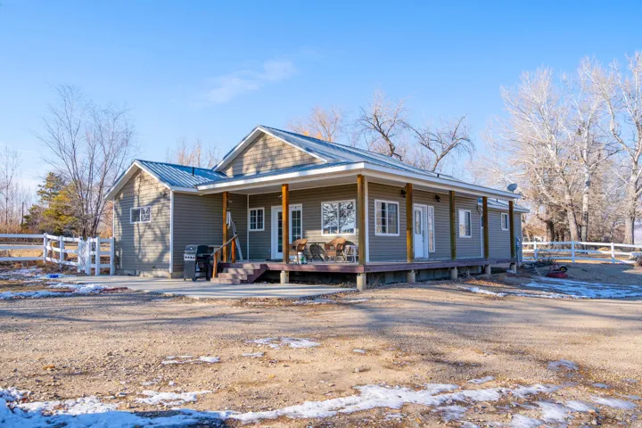 Snow covered back of property with covered porch and a metal roof