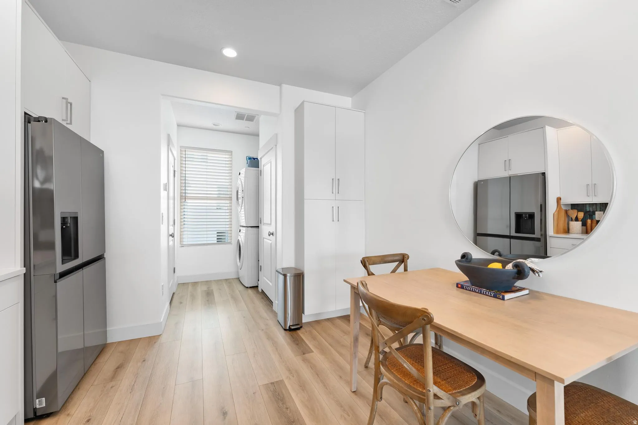Dining area with light wood finished floors and stacked washer / drying machine