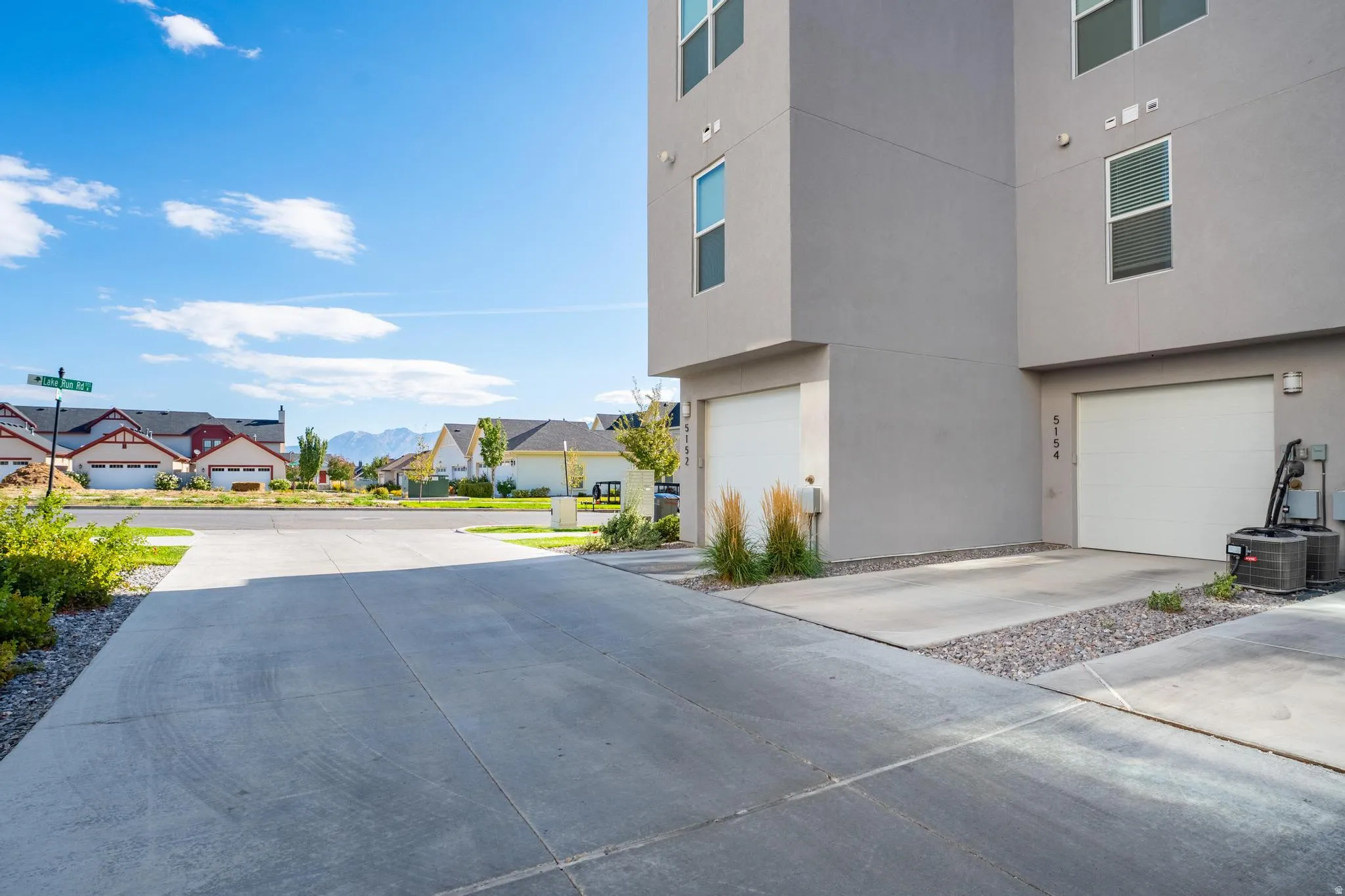 View of property exterior with a garage, stucco siding, concrete driveway, and a residential view