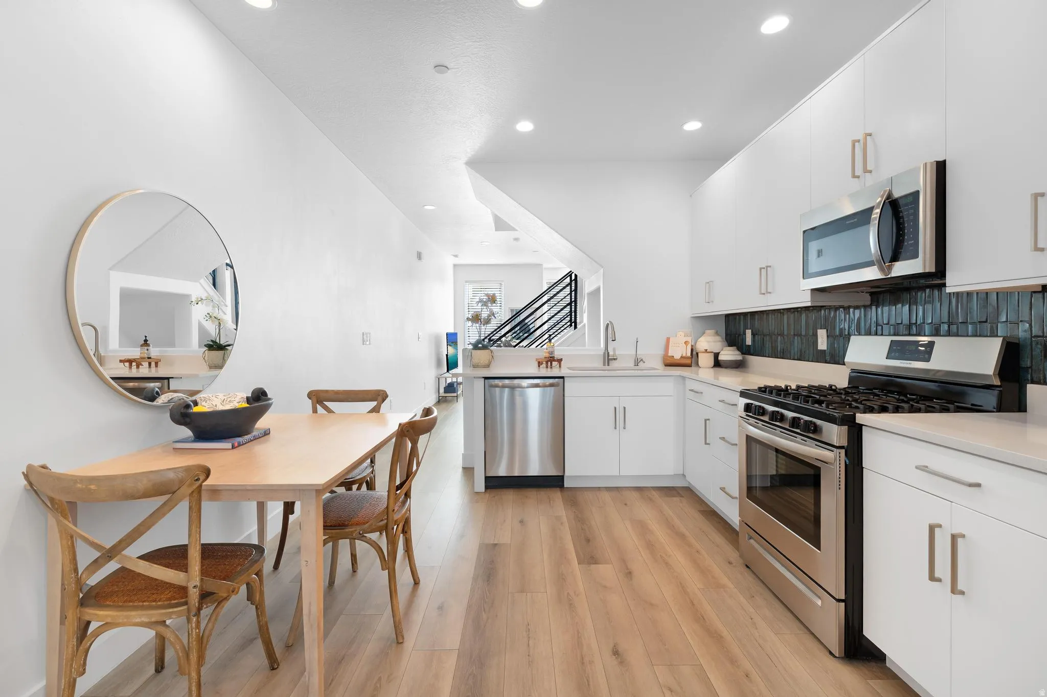 Kitchen featuring stainless steel appliances, white cabinets, light wood finished floors, a peninsula, and modern cabinets