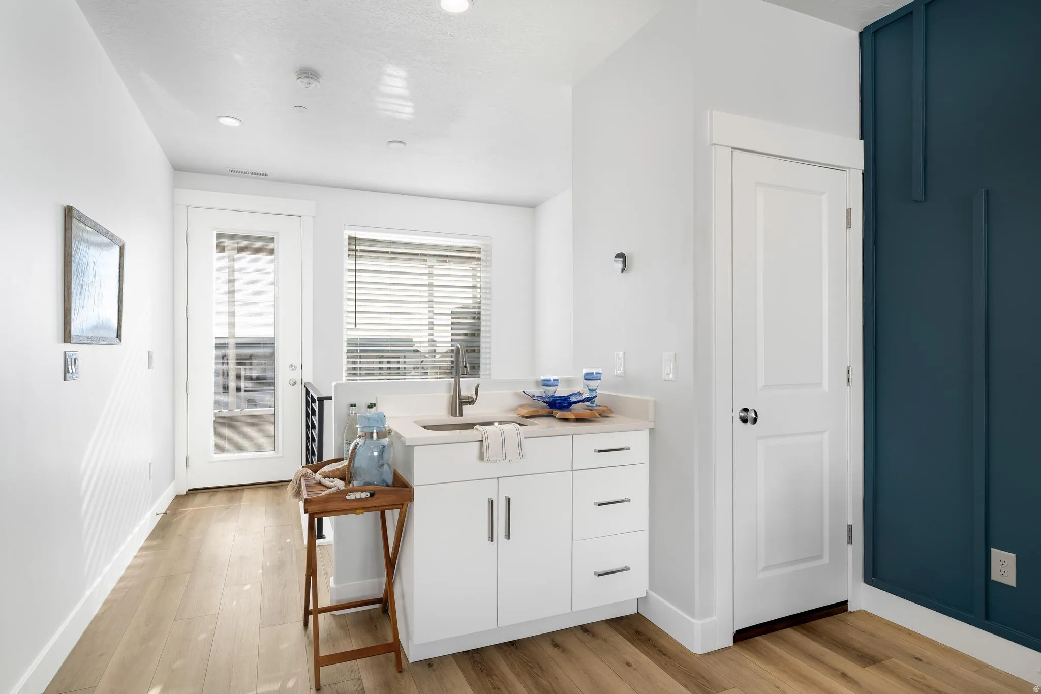 Interior space featuring white cabinets, light wood finished floors, recessed lighting, and light stone counters