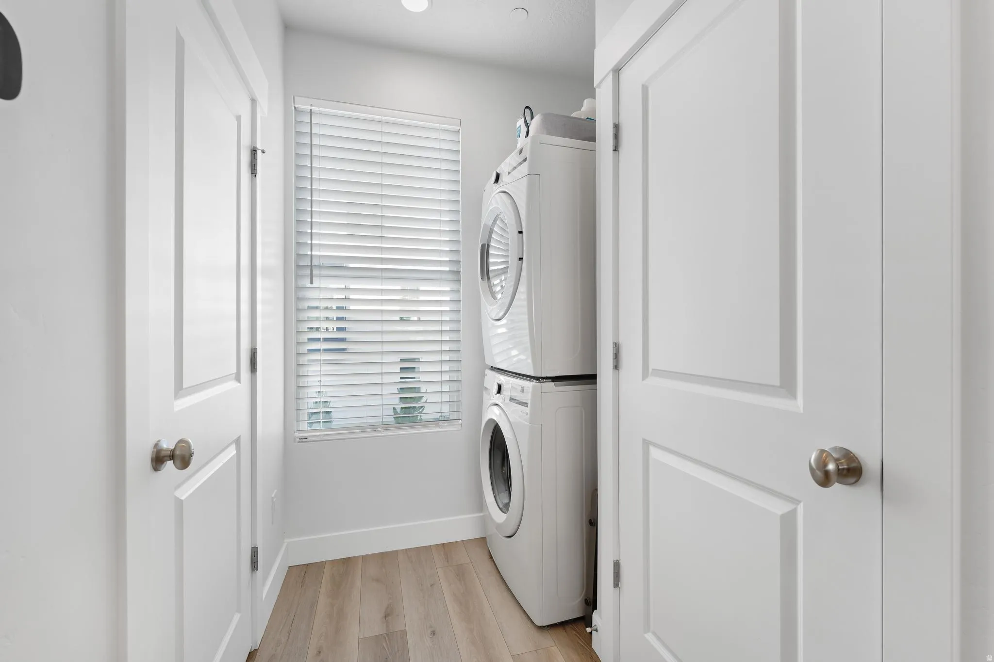 Laundry room featuring light wood-style flooring and stacked washer / drying machine