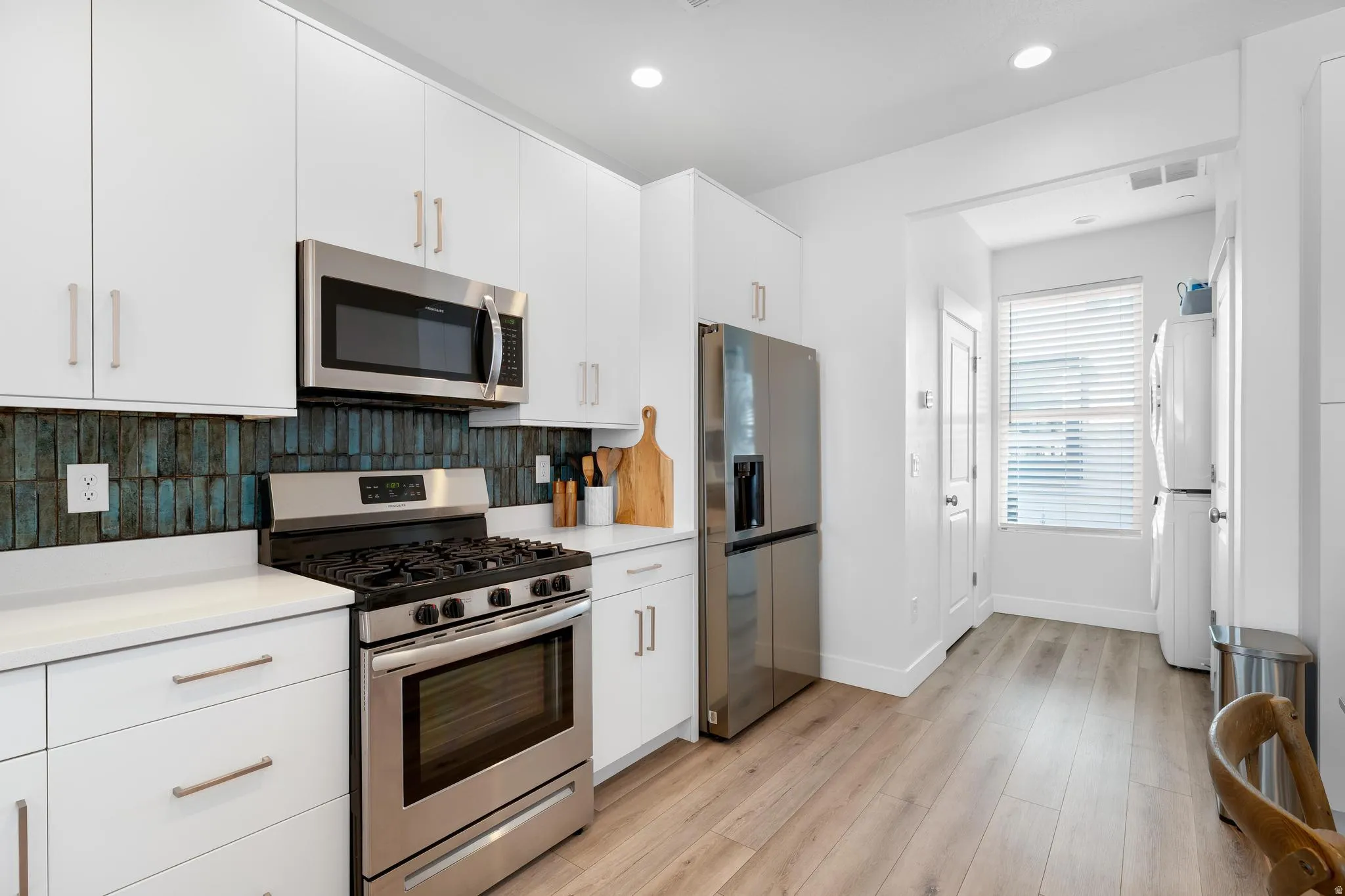 Kitchen featuring white cabinetry, appliances with stainless steel finishes, light wood finished floors, and recessed lighting