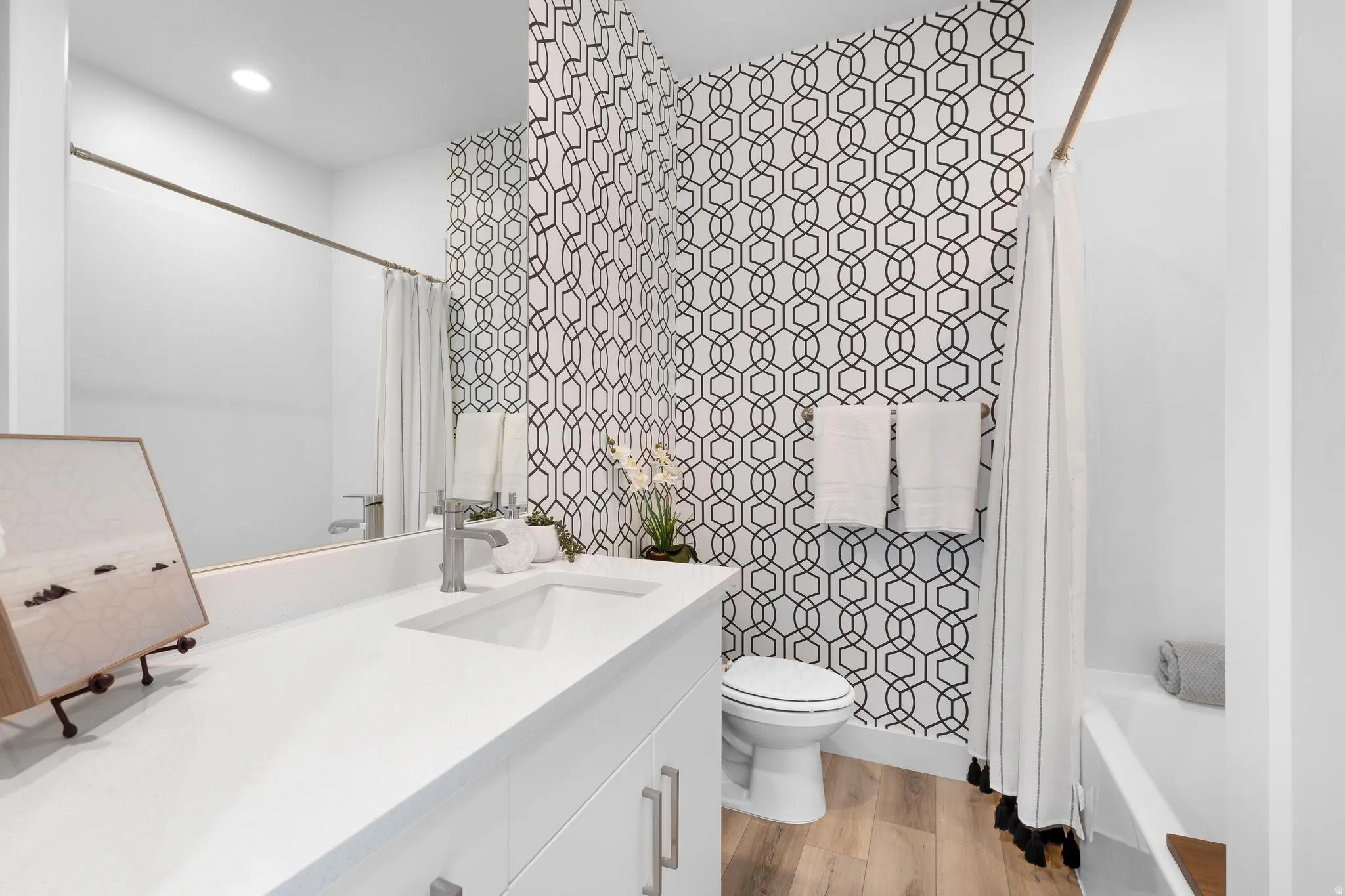 Full bathroom with vanity, shower / bath combo with shower curtain, light wood-style flooring, recessed lighting, and tile walls